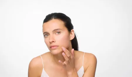 A woman examining her skin in the mirror as part of her clear skin routine